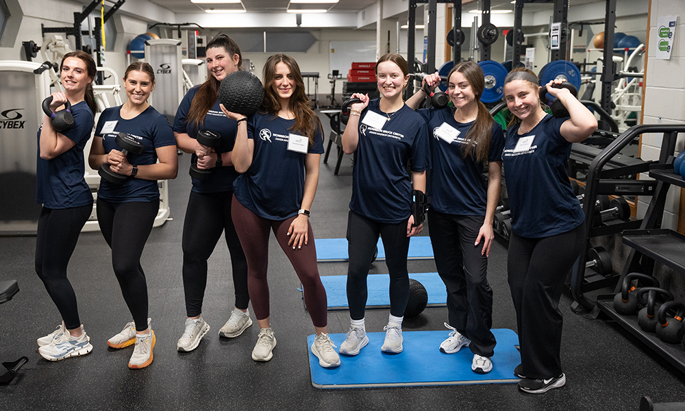 EmpowHER staff and volunteers showing their strength in a weight room