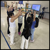 Children participating in a group activity using a hula hoop, promoting teamwork and physical activity.