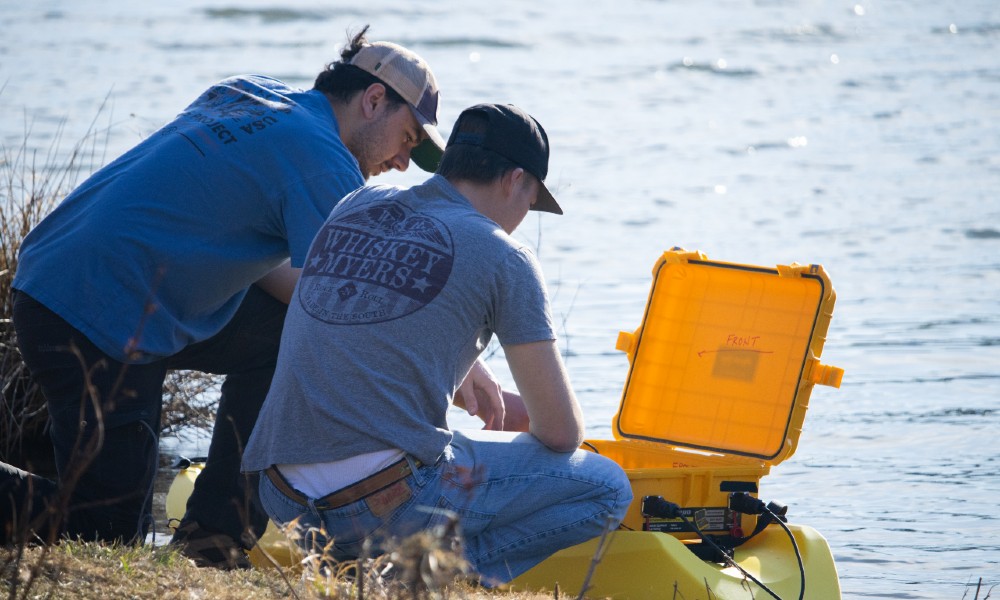 McIntyre and Horner review the drone’s control system before deployment, ensuring it's ready to collect bathymetric data from Newman Lake
