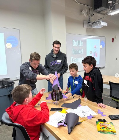 Grant (L) and Owen (R) are teaching middle school students about Newton's 3 Laws of Motion using bottle rockets.