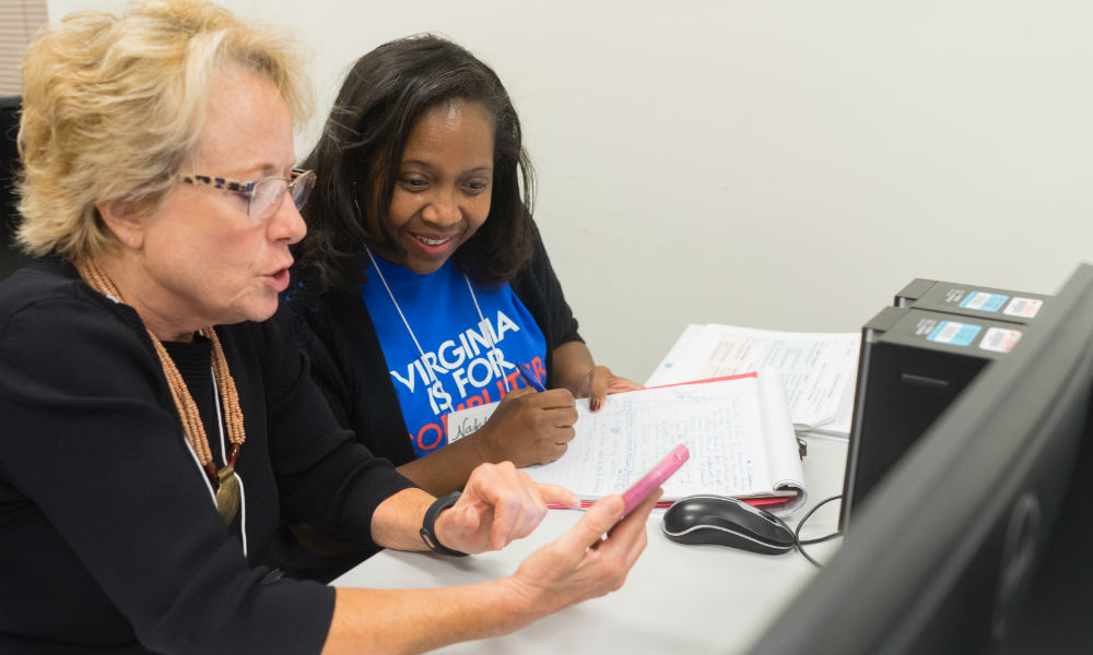 Two females looking at phone taking notes