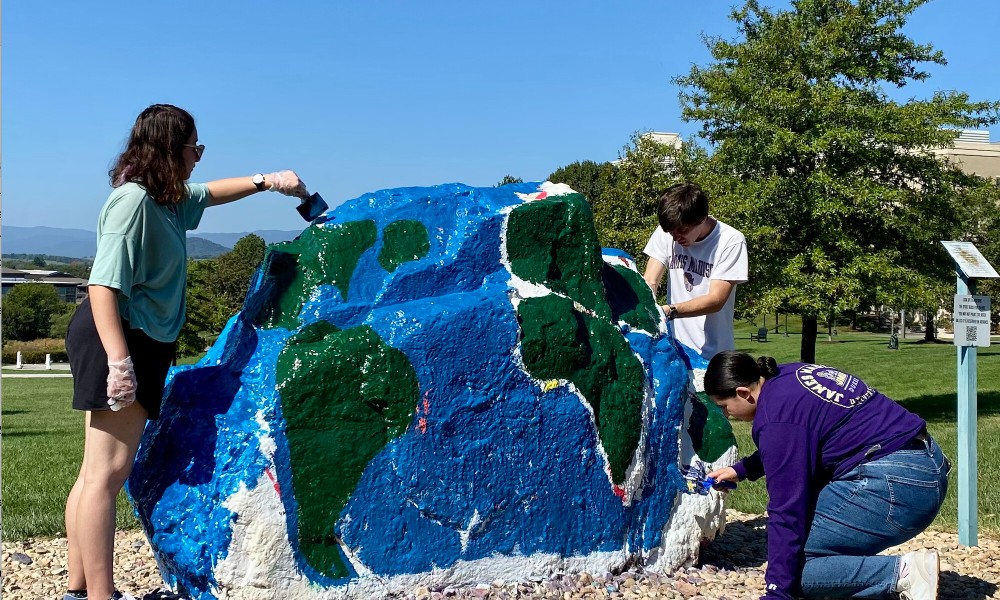 Geography students painting spirit rock
