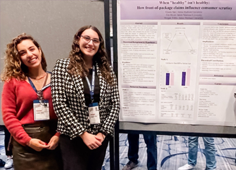 Dr. Gizem Atav, associate professor of Marketing, and senior Morgan Tribby, a Marketing and Business Management double-major stand beside a research poster they  presented to the university’s Board of Visitors on November 13