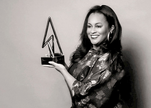 Black-and-white portrait of Alexis McCombs holding a trophy award against a plain backdrop.