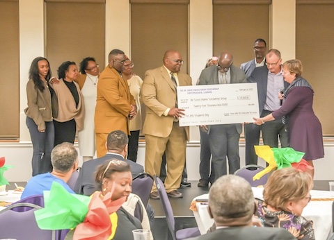 Nora Crouch (‘82) and Charles T. May Jr. (‘83) giving back by presenting a large check at the Ole School’s Heritage Month Celebration in 2023, surrounded by attendees celebrating the occasion.