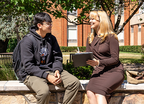 two students talking while sitting in a court yard