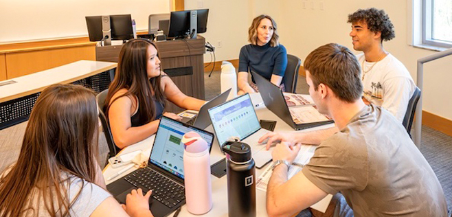 Small group of College of Business marketing students seated around a table developing real campaign strategies for the Dian Fossey Gorilla Fund.