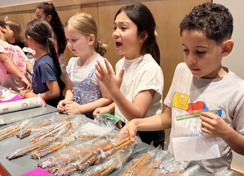 children displaying items for sale on a table