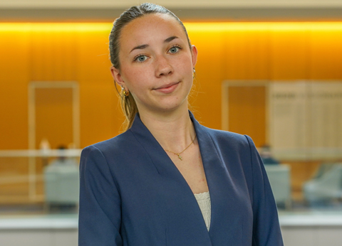 Portrait of a Magnolia Matzen in a blue blazer standing indoors in an office-like setting.