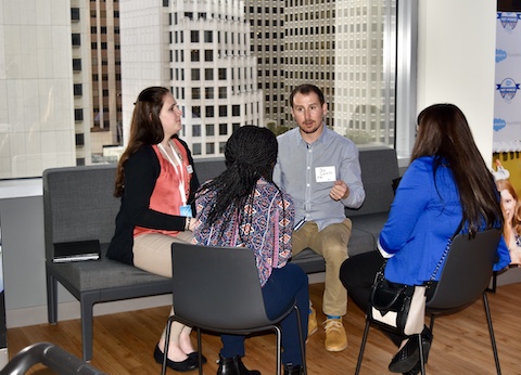 Students sitting at table with employer in office building with cityscape in background through window