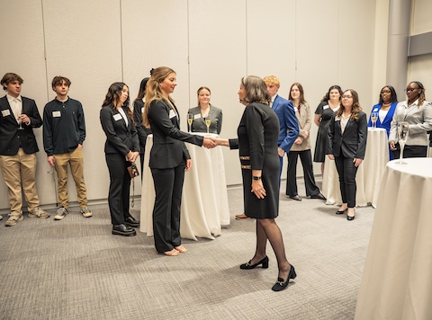 Students in professional attire learning how to give a professional handshake