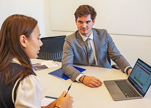 woman and man sit at a table with a laptop