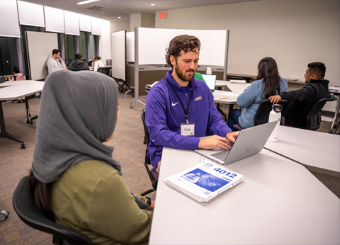 A volunteer MS in Accounting student helps a community member at a round table.