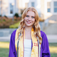 Rebecca Dubois standing in her graduate gown.