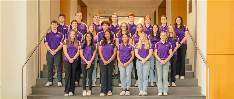 group of students with purple polos standing on the steps for a posed picture