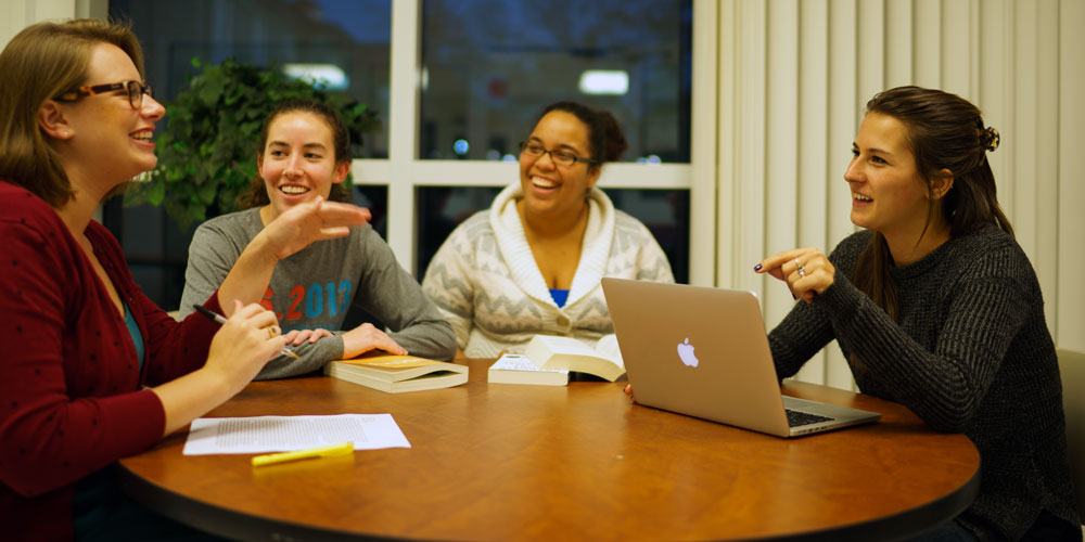 Four Communication and Advocacy graduate students work on a project