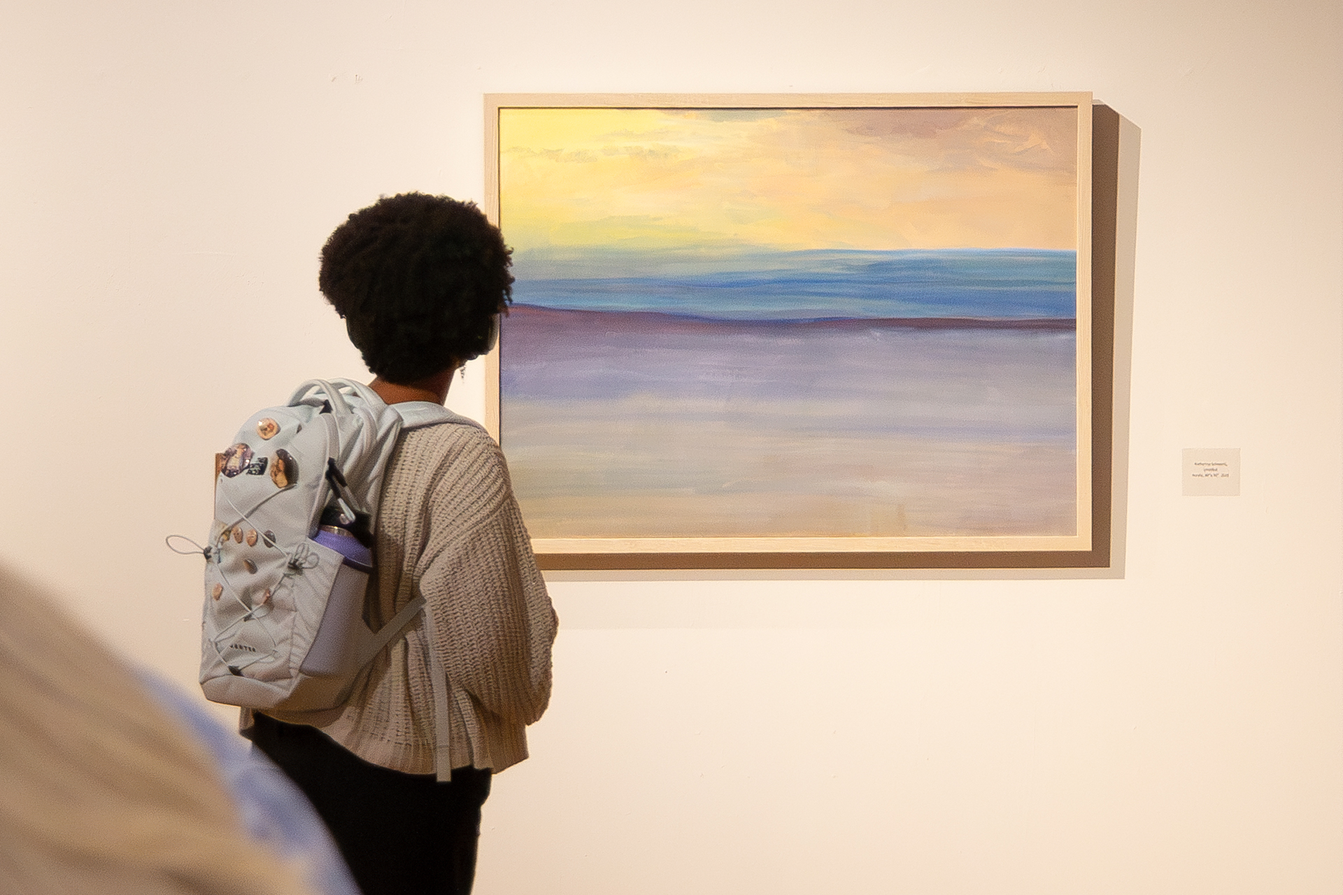 woman viewing painting of sunset