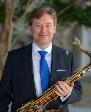 man smiling with a saxophone