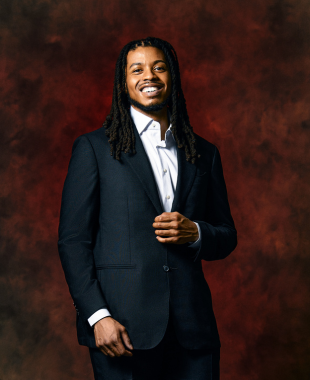 man standing in front of red backdrop smiling