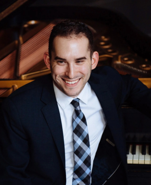 man smiling in front of piano