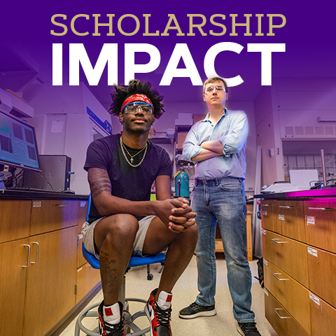 scholarship impact, student sitting and professor standing looking at camera in a science lab