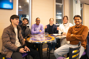 A group of international students smile for a photo while playing trivia