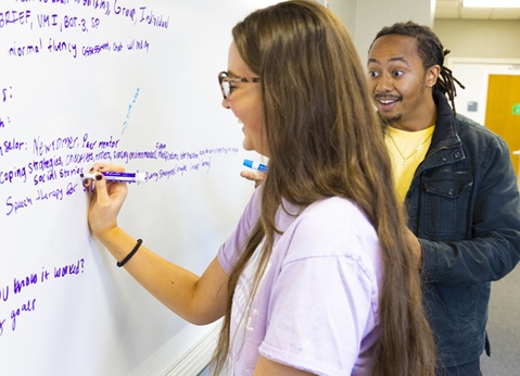 Two students collaborating at white board