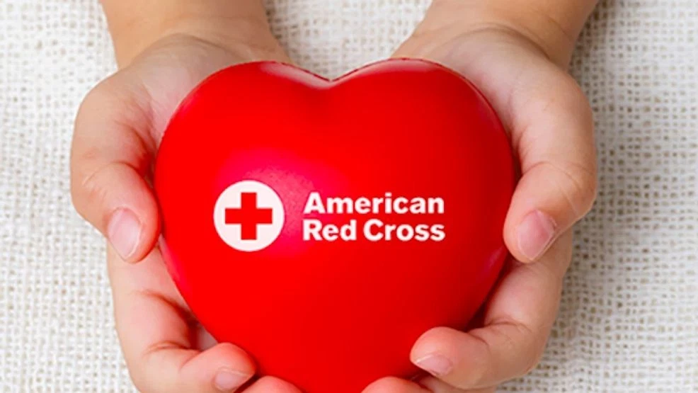Hands holding a red heart featuring the American Red Cross logo and name.