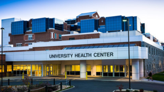 Exterior view of the University Health Center building with the main entrance and sign visible at dusk.