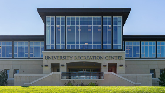 Front entrance of a modern building labeled “University Recreation Center,” with large glass windows.