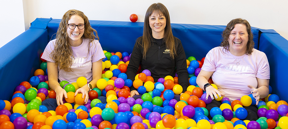 OTCES staff sitting in a tub of colorful balls