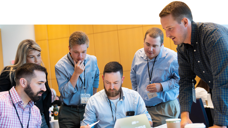 A group of professionals collaborating around a laptop during a meeting or workshop.