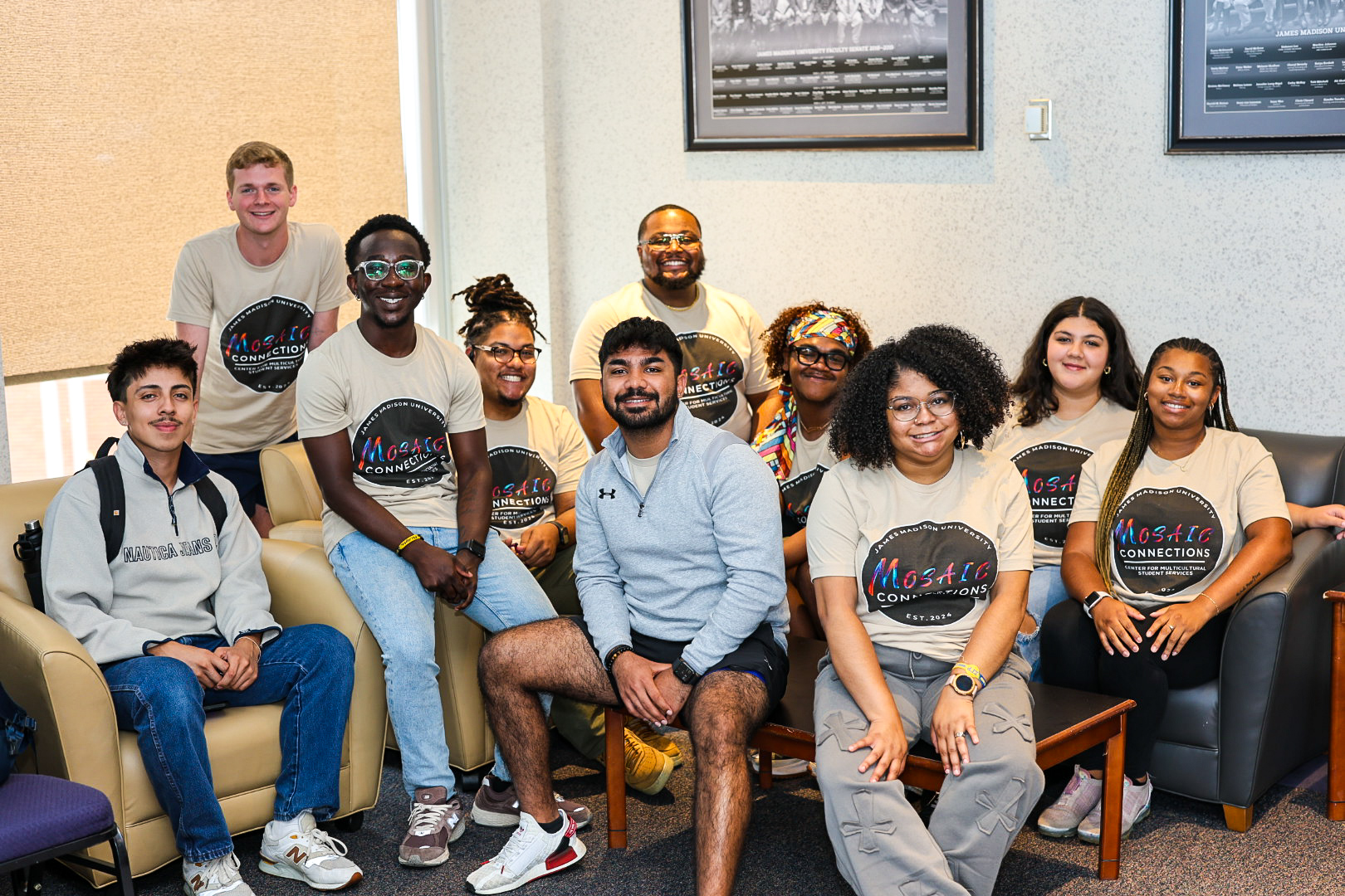 A group of diverse individuals smiling and posing together, wearing matching t-shirts that say "Mosaic Connections."