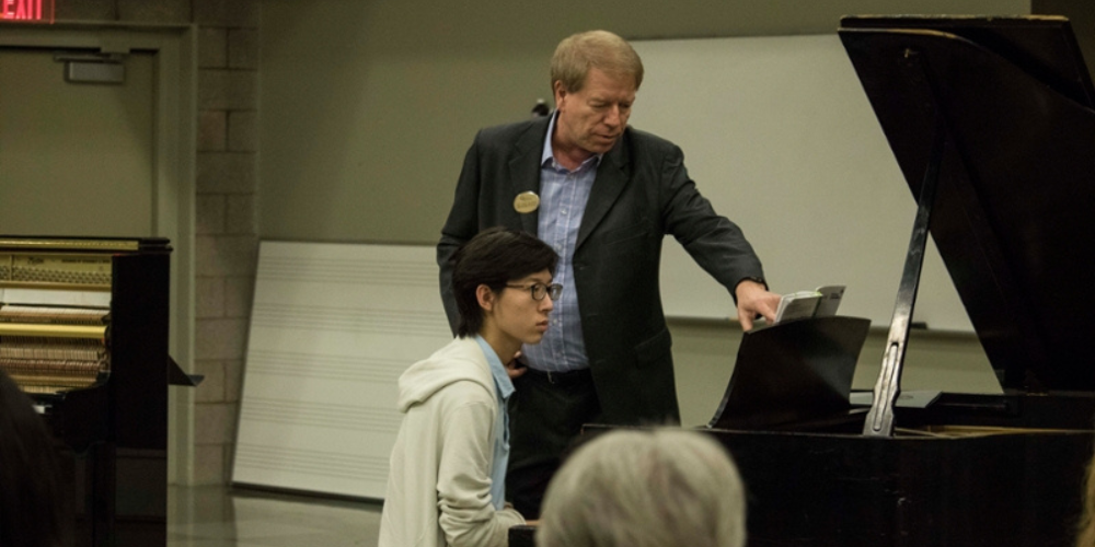 Piano professor working with piano student at piano