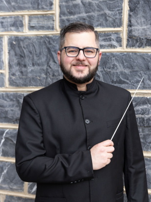 Man holding conducting baton and smiling at the camera