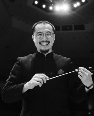 Man holding conducting baton and smiling at camera