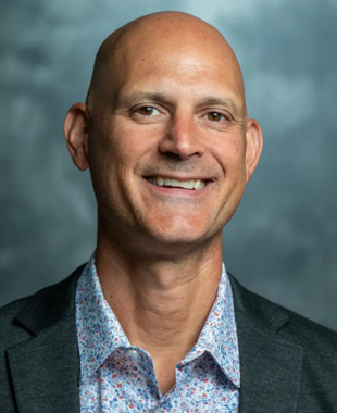 Man smiling at camera with blue backdrop