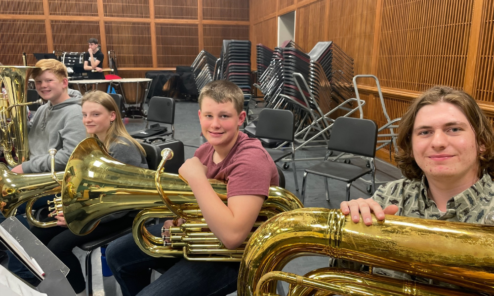 Students smiling while holding tubas