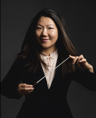 woman standing with a conducting baton between two fingers