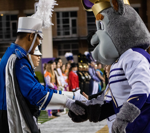 High school marching band member shaking Duke Dog's hand