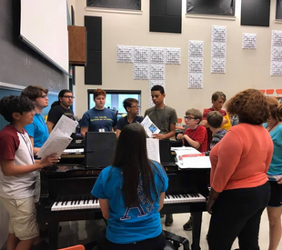 Students singing around a piano