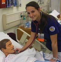 Photo of JMU nursing student Miriam Daoud using a stethoscope to listen to a mannequin's heart.