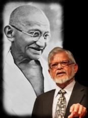 Photo of Arun Gandhi with a photo of his grandfather, Mahatma Gandhi, behind him