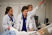 Photo of three JMU nursing students tending to a patient.