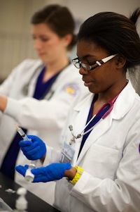 Photo of a JMU nursing student preparing an IV line for a patient.