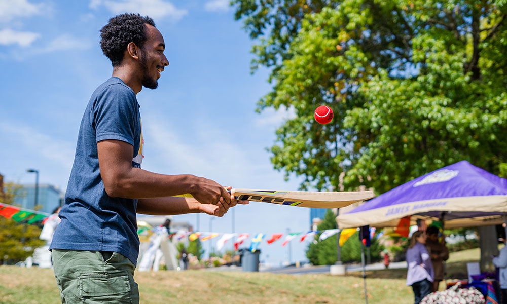 Male student plays with and ball and bat