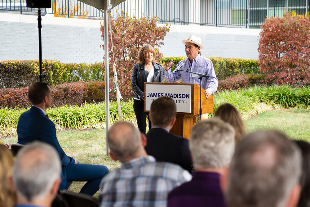 Paul Holland speaking at the podium next to Linda Yates