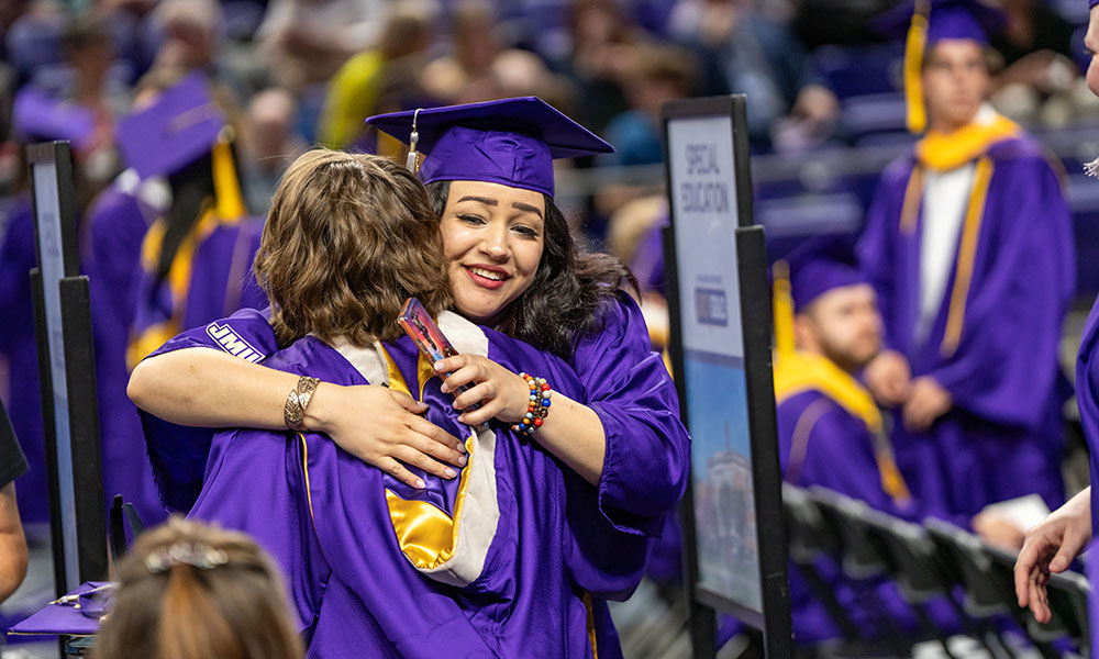 students in grad attire hugging