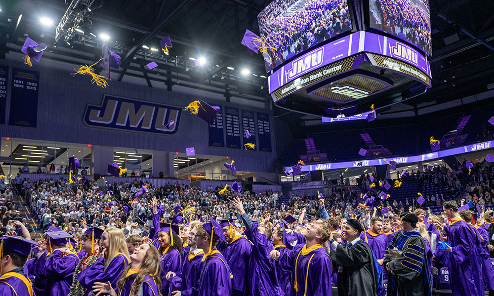Graduates throwing caps in the air in an arena
