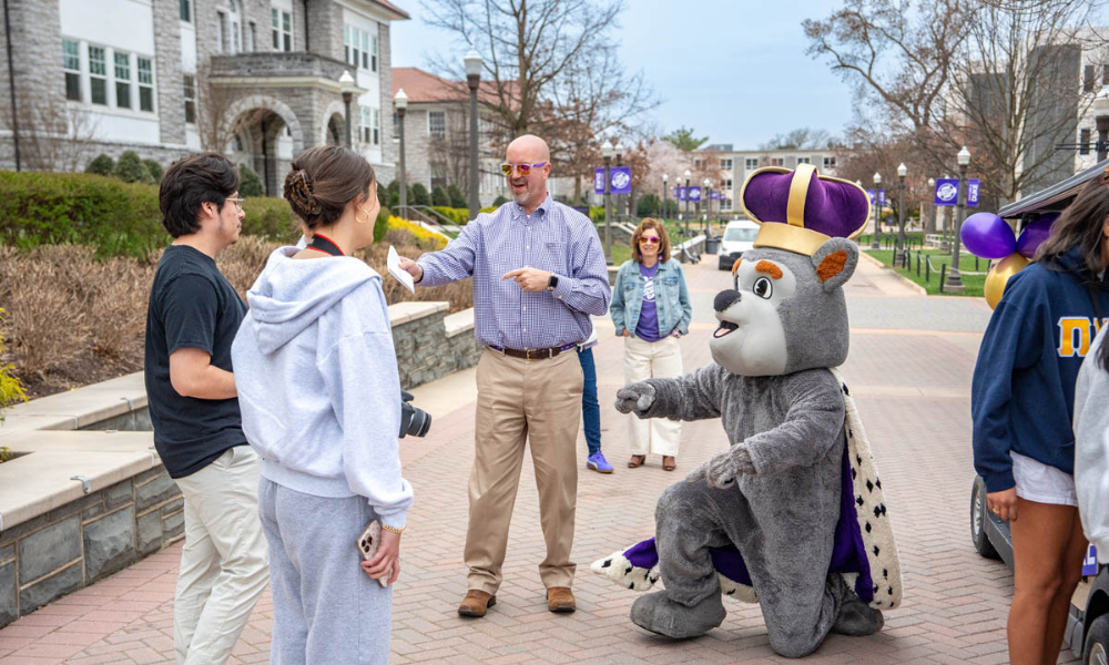 Dr. Tim Miller, vice president of student affairs interacting with students, Duke dog next to him